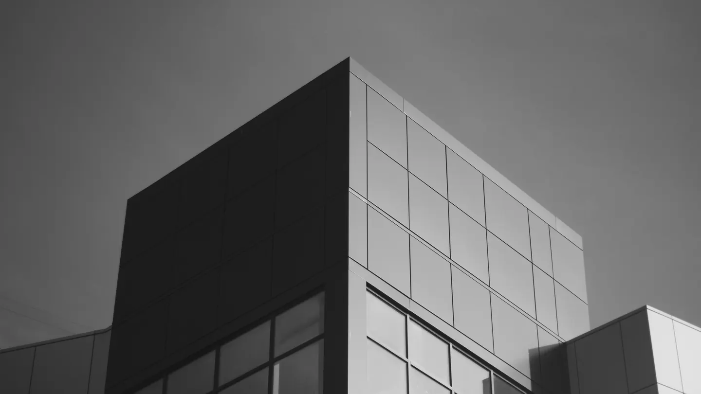 Quina de um edifício de concreto claro recortada contra o céu azul-petróleo.